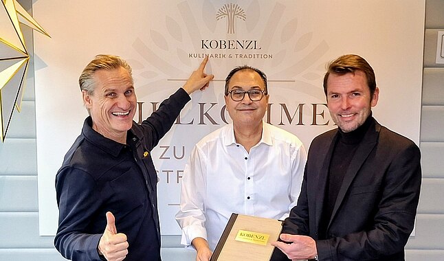 Drei Männer mit einer Urkunde.