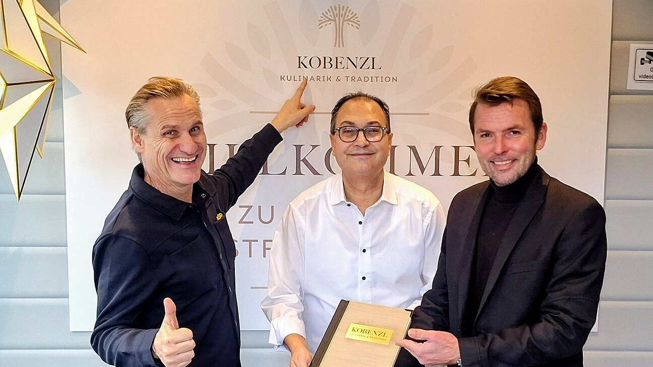 Drei Männer mit einer Urkunde.