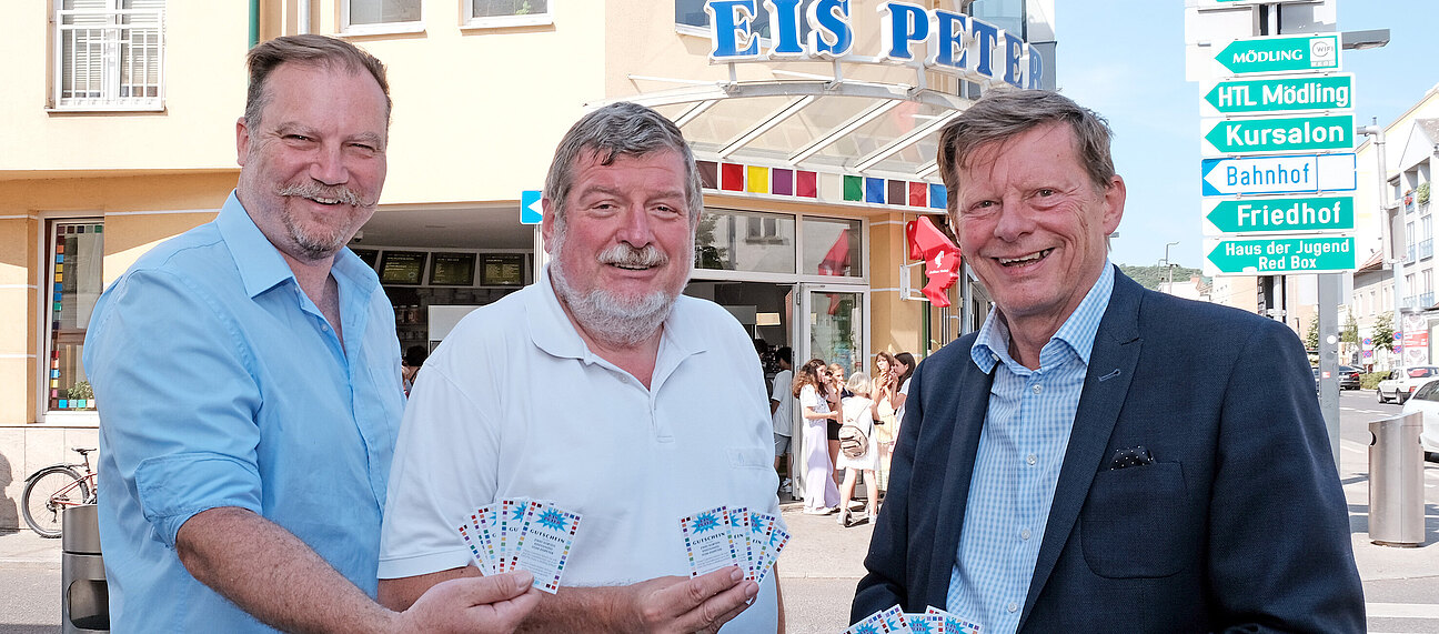 Drei Männer halten Gutscheine für Eis Peter.