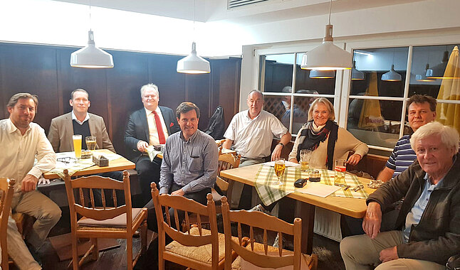 Mehrere Personen sitzen im einem Gasthaus-Saal.