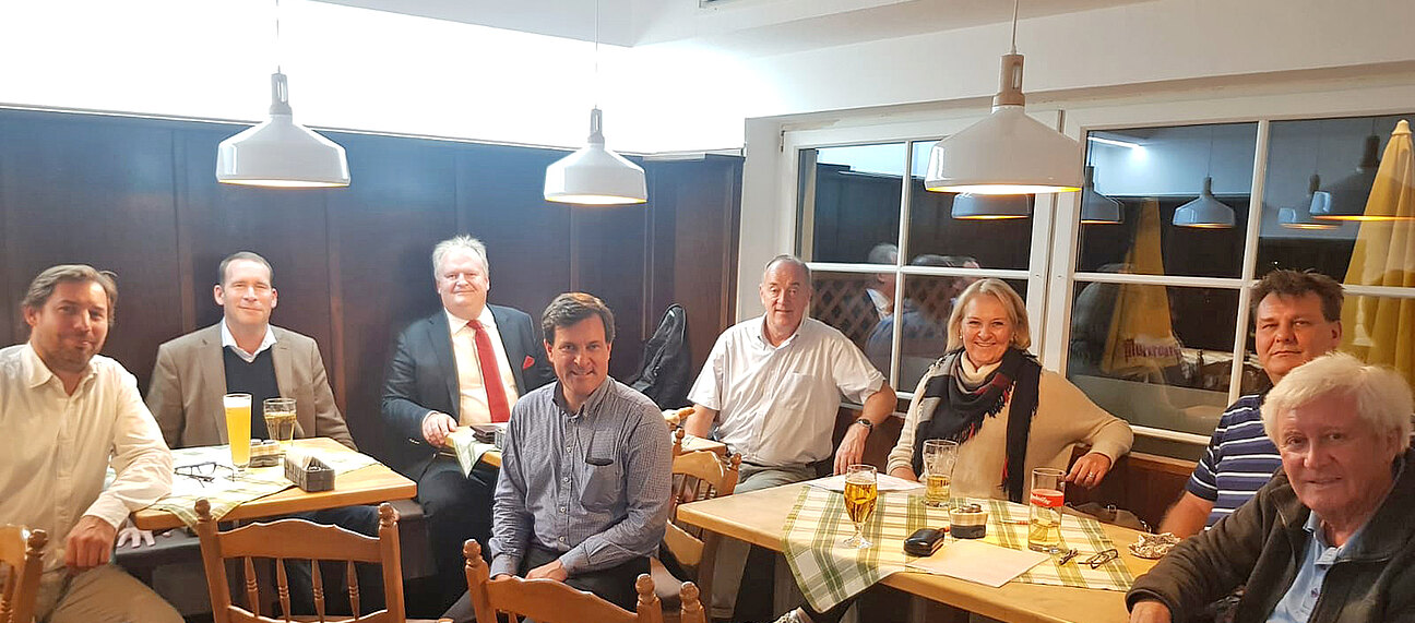 Mehrere Personen sitzen im einem Gasthaus-Saal.