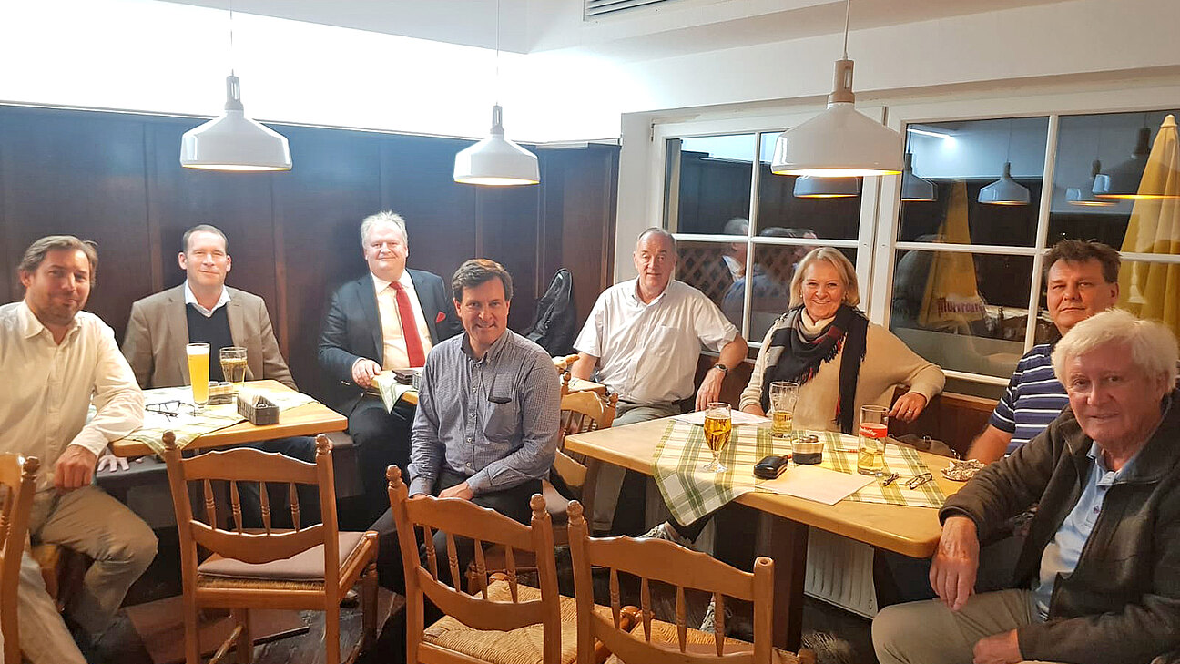 Mehrere Personen sitzen im einem Gasthaus-Saal.