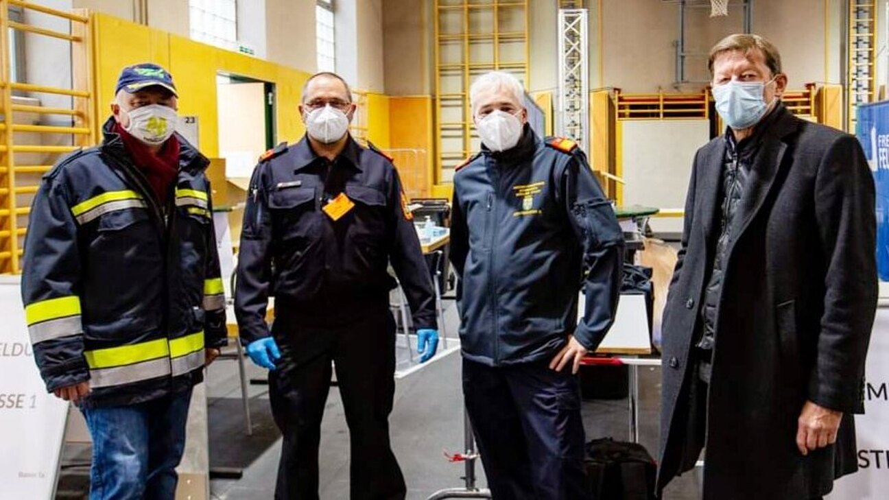 Vier Männer mit Mund-Nasen-Schutz in einer Turnhalle.