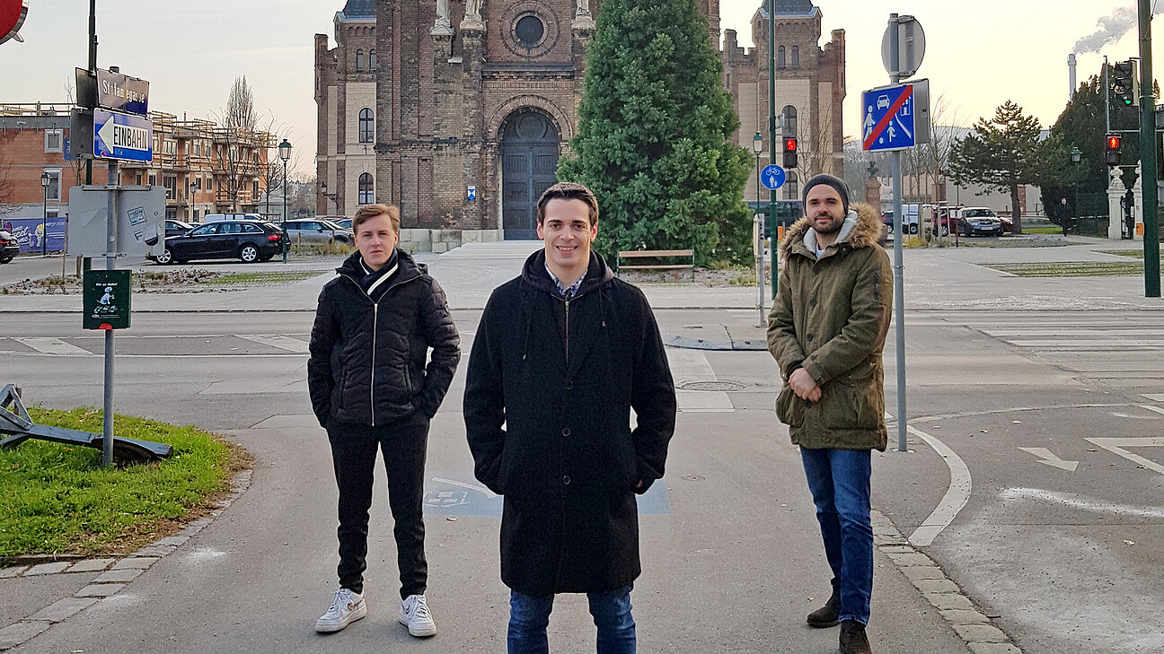 Drei Männer stehen auf dem Gehsteig gegenüber der Waisenhauskirche.